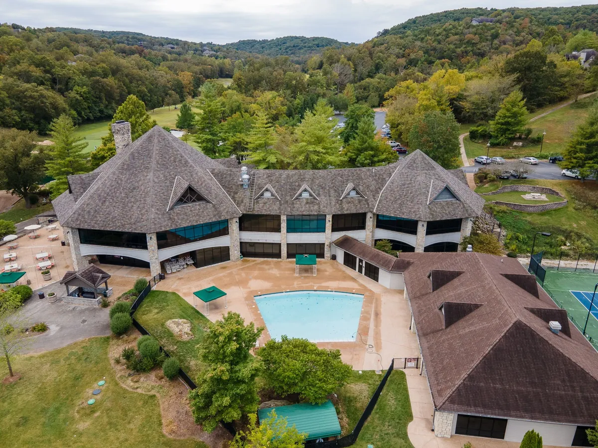 This image features a large, inviting outdoor pool surrounded by lush greenery and distinctive architectural elements. The serene environment suggests a well-maintained, upscale resort atmosphere, ideal for relaxation and leisure. The pool is a central amenity, reinforcing the promise of luxury and access to premium features.