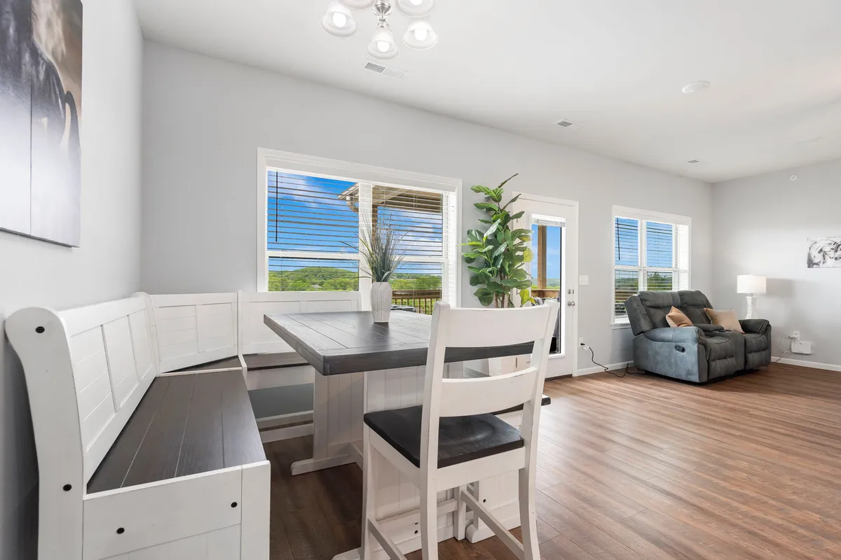 A cozy and inviting interior showcases a dining table, leather recliner, large windows with beautiful sunrise views, and an indoor plant. The space is filled with soft light, suggesting both relaxation and quality family time.