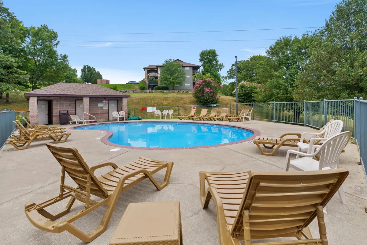 The image presents an inviting swimming pool area with lounge chairs, a poolside shed, and lush green landscaping. The pool is the centerpiece, suggesting a place to unwind, socialize, and enjoy sunny days together with friends or family.
