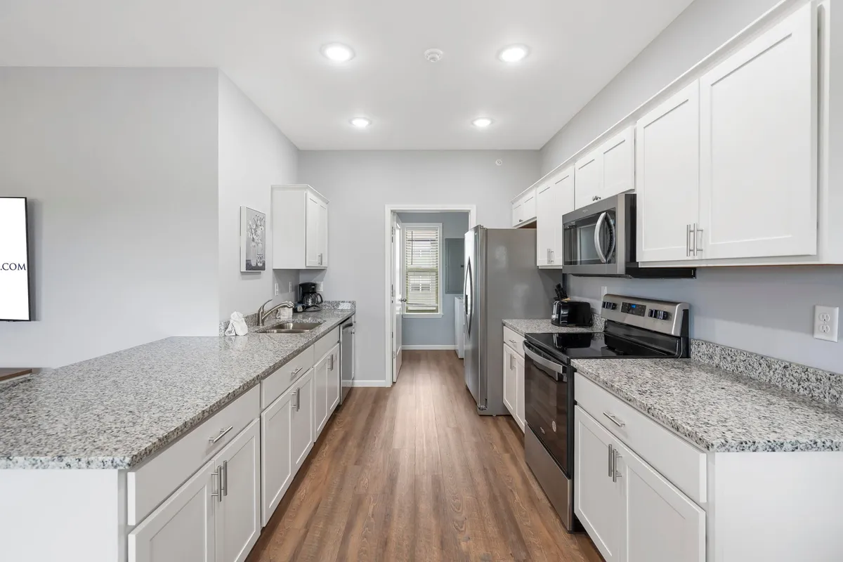 Another perspective of the kitchen highlights bright cabinetry, granite countertops, and stainless steel appliances. The space feels welcoming and functional, perfect for cooking, entertaining, and gathering loved ones.