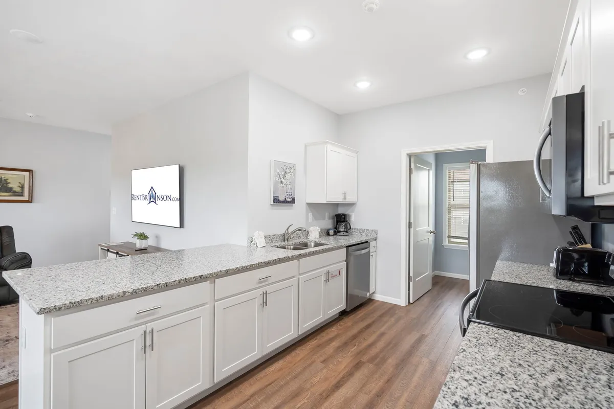 A stylish kitchen featuring granite countertops and contemporary appliances, offering a functional yet elegant space for cooking and socializing. The view into the kitchen supports the narrative of elevated cleanliness and comfort, aligning with the Rent Branson Clean Promise.