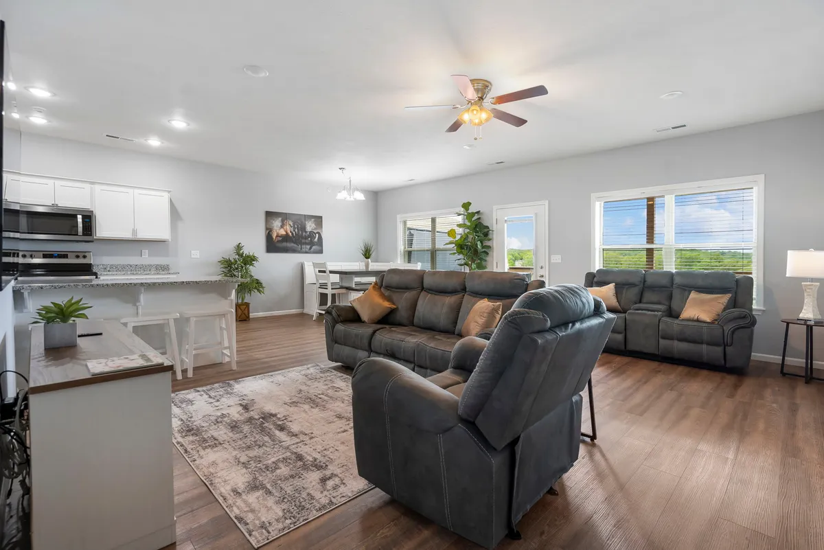 This image captures an open-concept interior scene featuring a comfortable seating area adjoining a dining table, with large windows bringing in natural light. The atmosphere is cozy and inviting, perfect for gatherings and casual meals, and the space exudes warmth and togetherness.